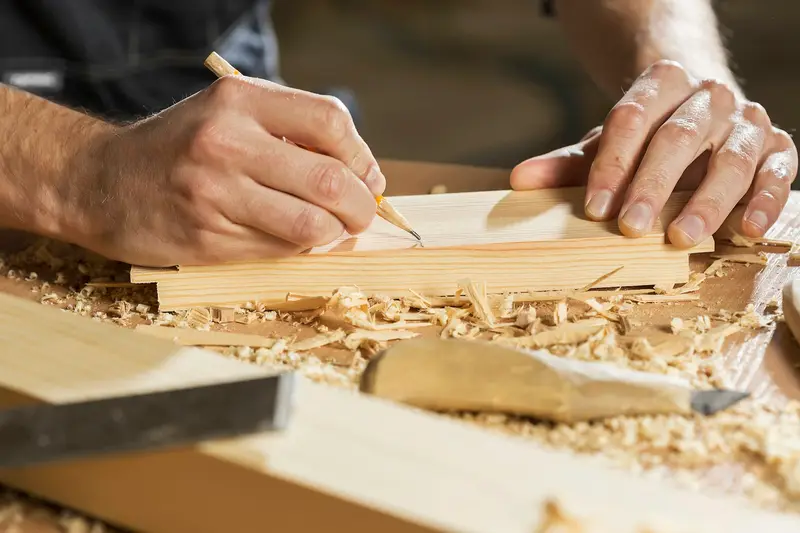 Mains traçant un repère au crayon sur une planche de bois